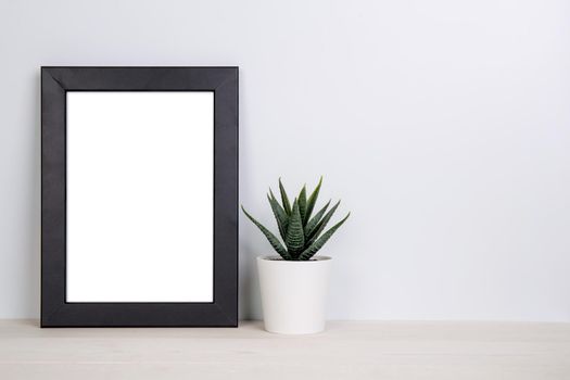 Mockup frame and plants in pot on table top at home, mock up poster for presentation on desk, indoor, your design for gallery photo and picture, border template and decoration for advertising.