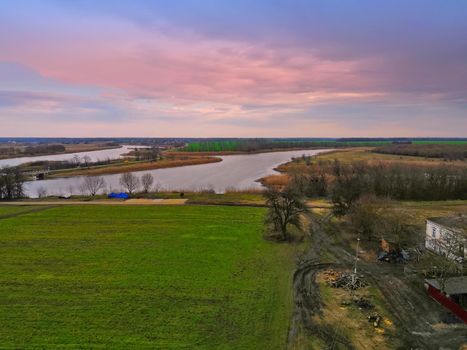 View of green field and big river with autumn forest, sunset, Russia