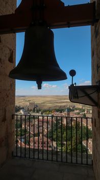 Bell tower of Cathedral of Segovia in Spain with Segovia Castle in the distance