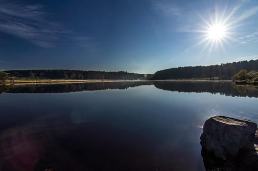 Beautiful blue sky over the lake and coniferous forest.