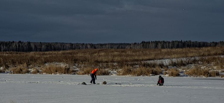 Fishermen on the river on winter fishing. Ice on the river and people on the people.