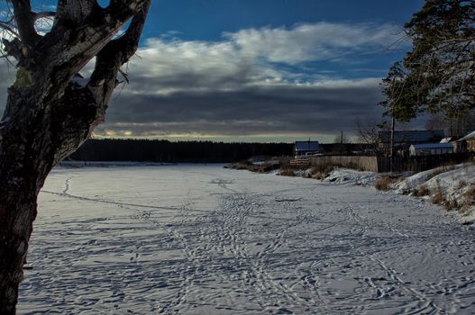 A house by a pond in winter in the snow. Life in nature by the water.