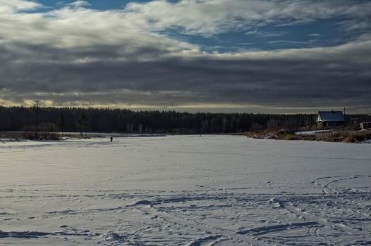 A house by a pond in winter in the snow. Life in nature by the water.