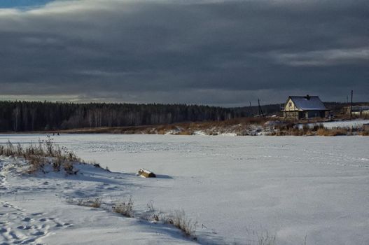 A house by a pond in winter in the snow. Life in nature by the water.