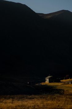 A wooden house on a hill in the altai at the foot of the high mountains.