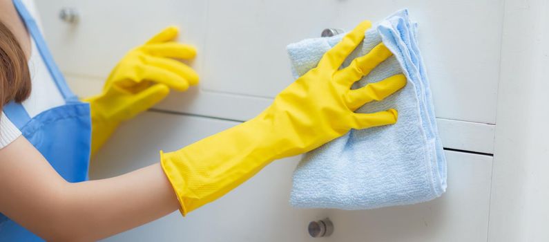 Young asian woman in face mask and gloves cleaning home in room, housekeeper is wipe with fabric, housemaid and service, worker polish dust, housework and domestic, lifestyle concept, banner website.