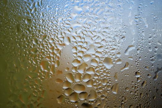 Condensation with beaded moisture droplets on the outside of a cold glass or bottle in a close up full frame background texture