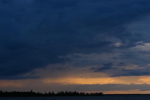 The sky is in zagon with clouds above the pond. Sunset time.