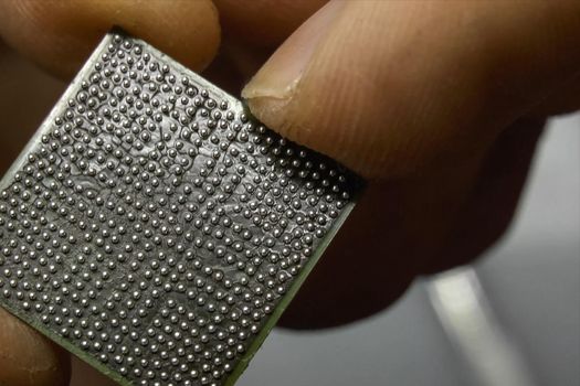 The recovered computer microprocessor chip is in the hands of a man.