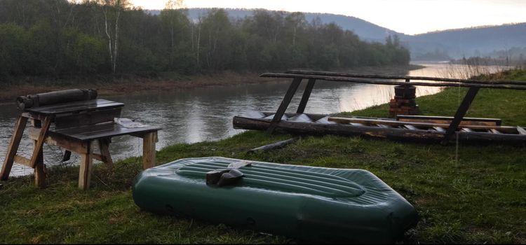 Inflatable boat on the shore at the pier on the river. Siberian Rivers