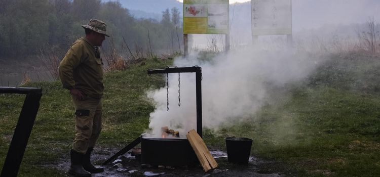 Surgut, Russia - July 12, 2019: A man lit a fire on the river bank.