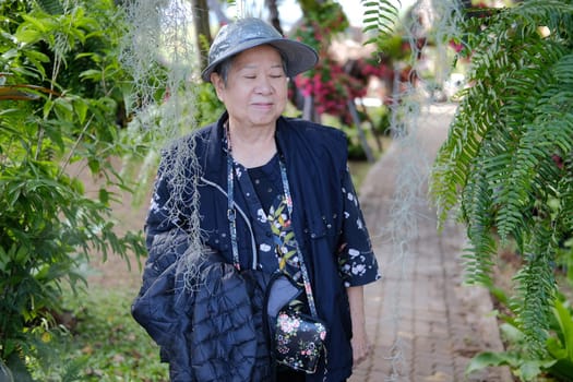 asian old elderly female elder woman resting relaxing in garden. senior leisure lifestyle