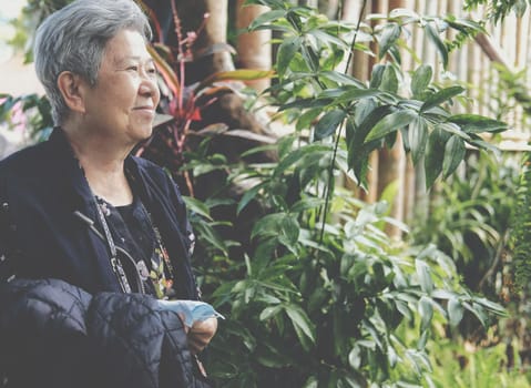 asian old elderly female elder woman resting relaxing in garden. senior leisure lifestyle