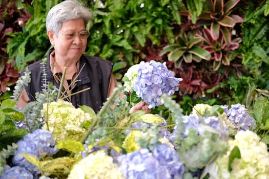 cheerful old asian elderly senior elder woman holding hydrangea flower bouquet