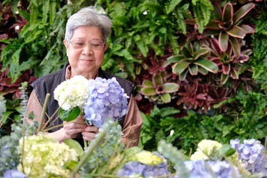 cheerful old asian elderly senior elder woman holding hydrangea flower bouquet