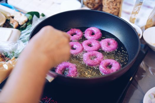 frying purple sweet potato doughnut. deep fried doughnuts dessert