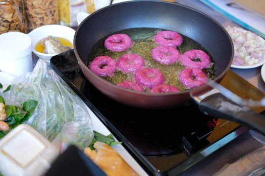 frying purple sweet potato doughnut. deep fried doughnuts dessert