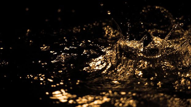 Hi speed close up images of oil liquid from diesel gasoline splashing and moving up to the air on black background for represent power of fuel liquid that active and powerful. studio shot premium gold color tone.