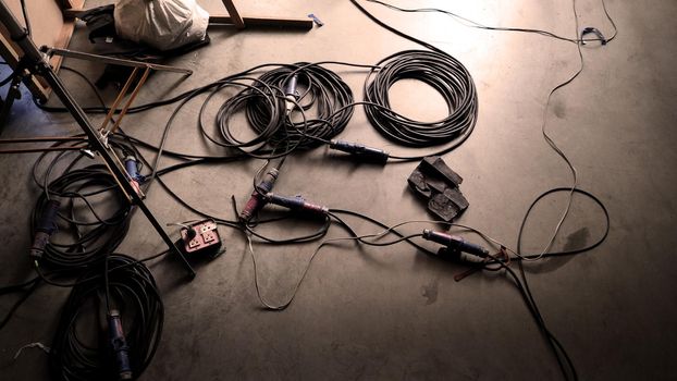 Background studio floor of filming or making of video production that include professional equipment such as many electric light wire and tripod and dolly wheel on it and look messy and a bit dirty.