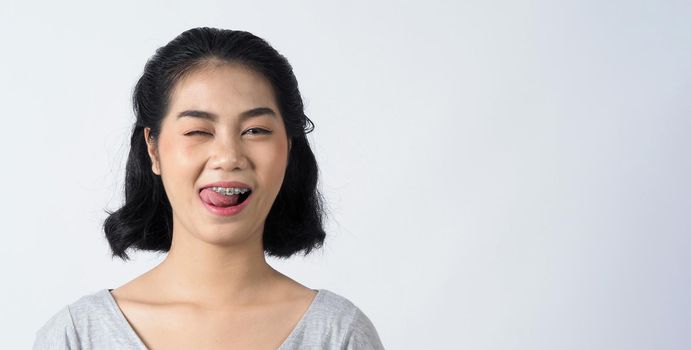 Dental braces of teen asian woman wearing braces teeth and contact lenses, she very confident and proudly present herself and smile on white background studio shot, Happiness teenager smiling facial expression.