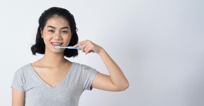 Dental braces of teen asian woman wearing braces teeth and contact lenses, she very confident and proudly present herself and smile on white background studio shot, Happiness teenager smiling facial expression.
