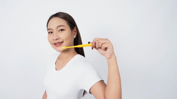 Asian teen facial with braces and toothbrush smiling to camera to show dental orthodonic teeth which include professional metal wire material from orthodontist. studio shot white background. Dental brace concept.