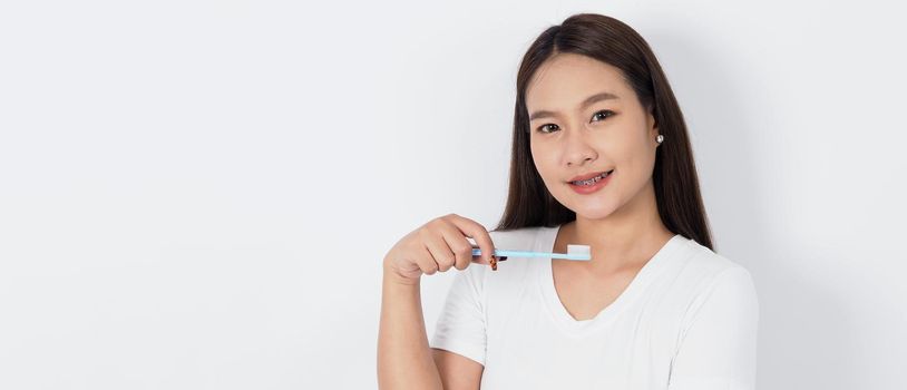 Asian teen facial with braces and toothbrush smiling to camera to show dental orthodonic teeth which include professional metal wire material from orthodontist. studio shot white background. Dental brace concept.