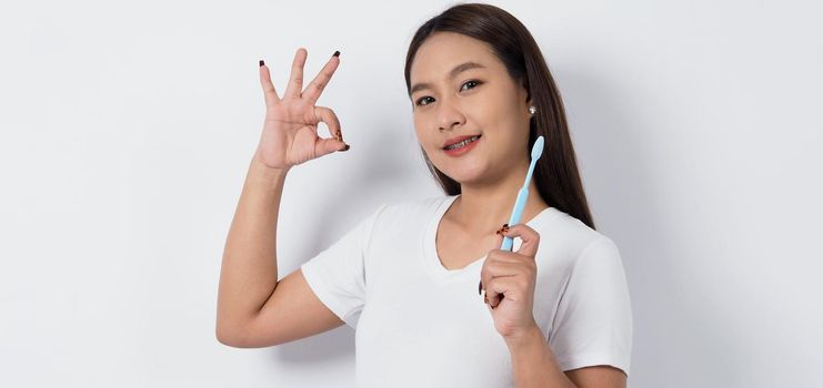 Asian teen facial with braces and toothbrush smiling to camera to show dental orthodonic teeth which include professional metal wire material from orthodontist. studio shot white background. Dental brace concept.