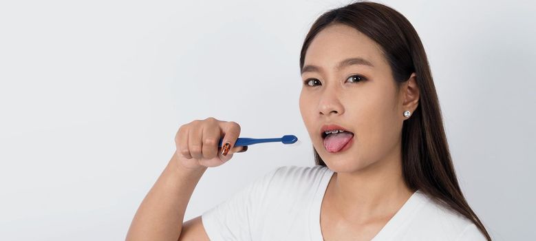 Asian teen facial with braces and toothbrush smiling to camera to show dental orthodonic teeth which include professional metal wire material from orthodontist. studio shot white background. Dental brace concept.