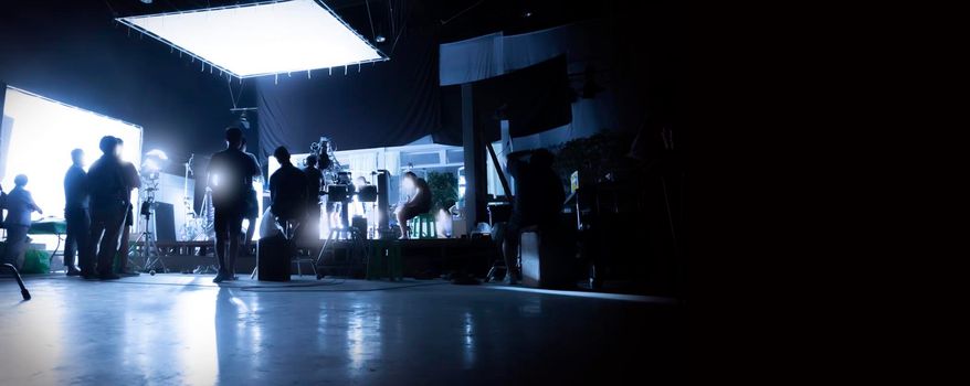 Silhouette images of video production behind the scenes or b-roll or making of TV commercial movies that film crew team lightman and videos cameraman working together with movie director in studio.