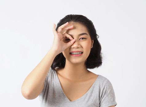 Dental brace beautiful girl smiling looking on a camera. white teeth with blue braces. Dental care. Asian teen woman smile with orthodontic accessories. Cosmetic dentistry, orthodontics treatment. white background studio.