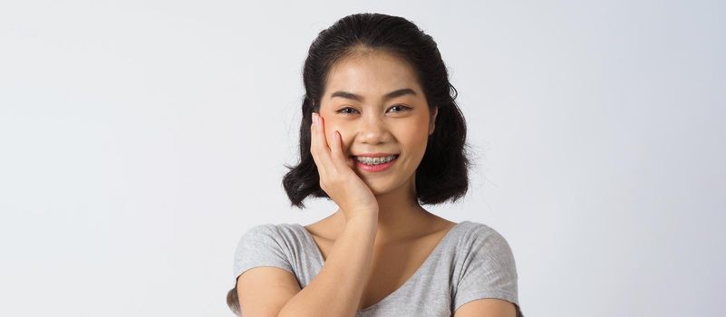 Dental brace beautiful girl smiling looking on a camera. white teeth with blue braces. Dental care. Asian teen woman smile with orthodontic accessories. Cosmetic dentistry, orthodontics treatment. white background studio.