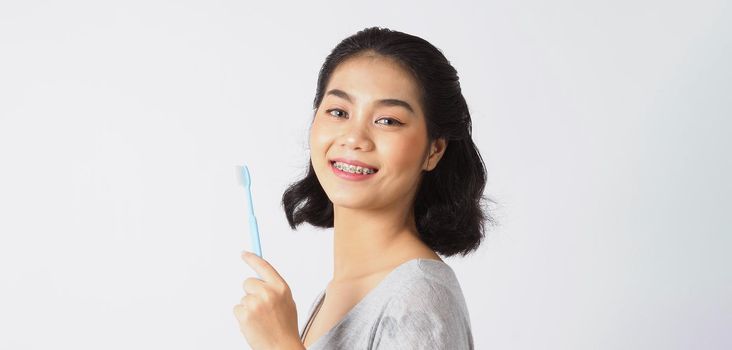 Dental brace teen girl smiling looking on a camera. white teeth with blue braces. Dental care. Asian woman smile with orthodontic accessories. Cosmetic dentistry, orthodontics treatment. studio shot.