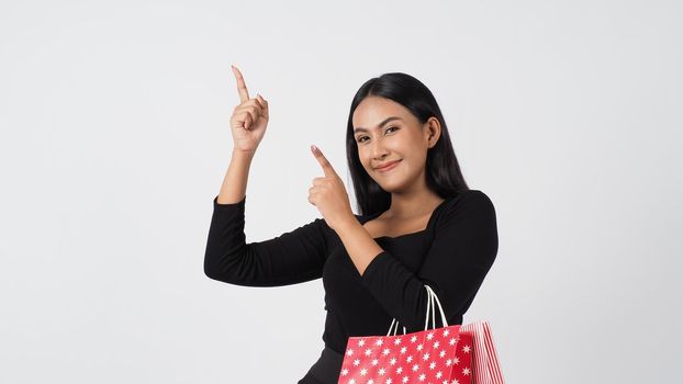 Happy shopping concept. Young asian Thai woman in action or activity of purchasing goods from stores or online shop. Happily girl and shopping bags during sale season in studio white background