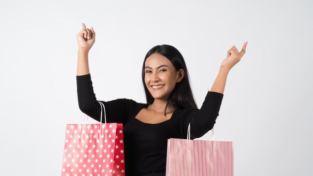 Happy shopping concept. Young asian Thai woman in action or activity of purchasing goods from stores or online shop. Happily girl and shopping bags during sale season in studio white background