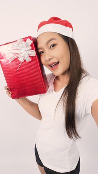 Girl hold gift box make selfie or video online with x-mas christmas prop decoration. Asian Thai teen woman taking online-selfie to celebrate festive season with her friend by red giftbox. studio shot.