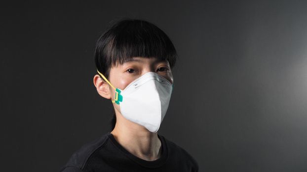 Asian girl in a mask on a black background in Coronavirus Quarantine situation. Title about the outbreak of the corona virus in the World, illness. Epidemic. female wearing N95 mask studio black background