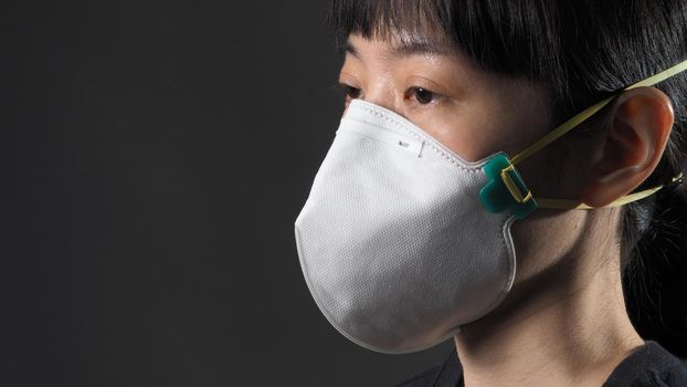 Asian girl in a mask on a black background in Coronavirus Quarantine situation. Title about the outbreak of the corona virus in the World, illness. Epidemic. female wearing N95 mask studio black background