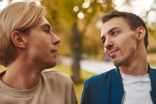 Loving gay couple outdoors. Two handsome men having romantic date in park. LGBT concept.