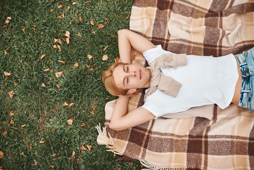 Handsome man having rest outdoors. Lying on blanket in park.
