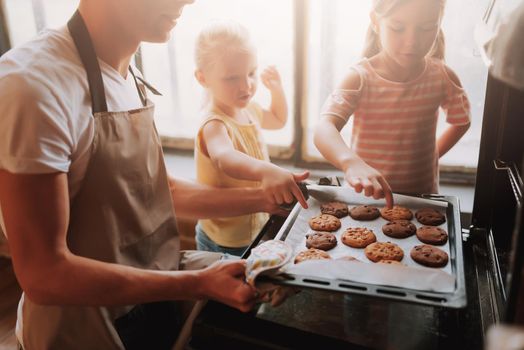 Cropped image of young father with two cute daughters cooking on kitchen. Family making cookies together at home.