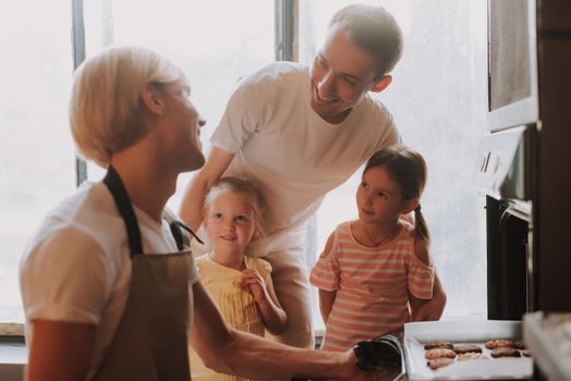 Gay couple with their adopted cute daughters cooking on kitchen. Lgbt family at home. Happy family making cookies together.