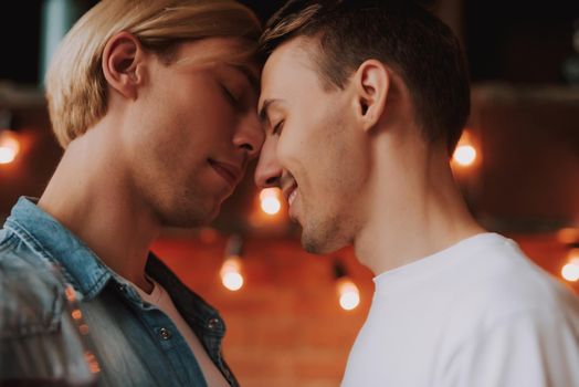 Loving gay couple at home. Two handsome men hugging and kissing on kitchen. LGBT concept.