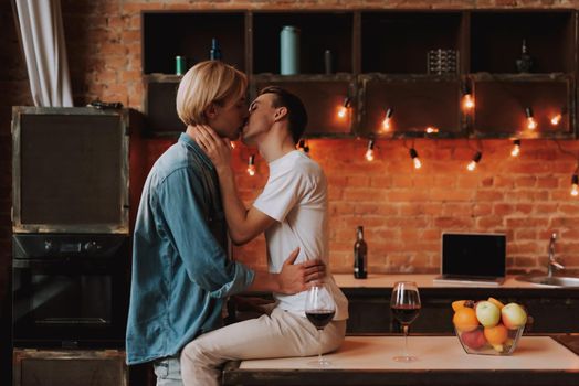 Loving gay couple at home. Two handsome men hugging and kissing on kitchen. LGBT concept.