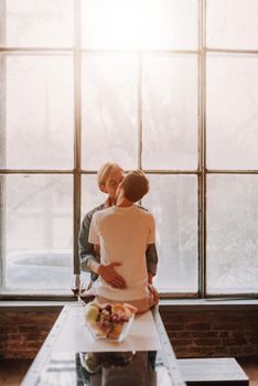 Loving gay couple at home. Two handsome men hugging and kissing on kitchen. LGBT concept.