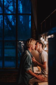 Loving gay couple at home. Two handsome men hugging and kissing on kitchen. LGBT concept.