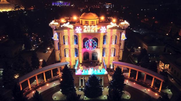 The city is decorated for Christmas and new year. Buildings, garlands, Christmas trees, fences and the square glow with different lights. People relax, enjoy the winter and holiday. View from a drone