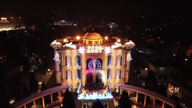 The city is decorated for Christmas and new year. Buildings, garlands, Christmas trees, fences and the square glow with different lights. People relax, enjoy the winter and holiday. View from a drone