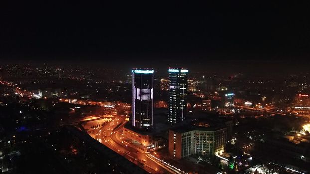 The city is decorated for Christmas and new year. Buildings, garlands, Christmas trees, fences and the square glow with different lights. People relax, enjoy the winter and holiday. View from a drone