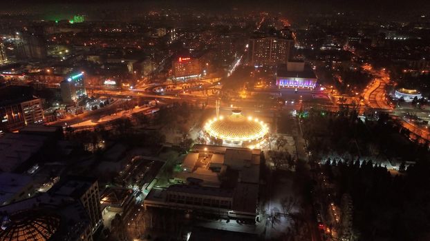 The city is decorated for Christmas and new year. Buildings, garlands, Christmas trees, fences and the square glow with different lights. People relax, enjoy the winter and holiday. View from a drone